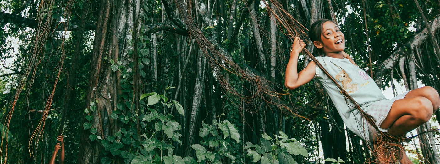 Girl swinging from tree vines in forest